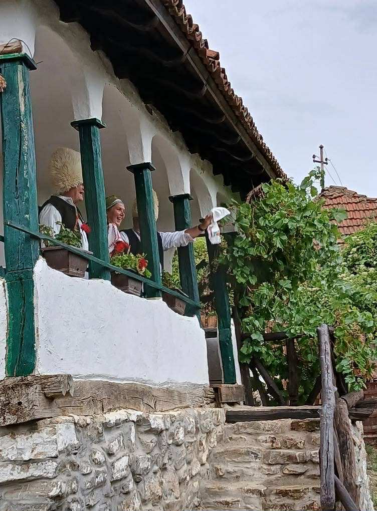 Ľudia v tradičných krojoch na verande domu